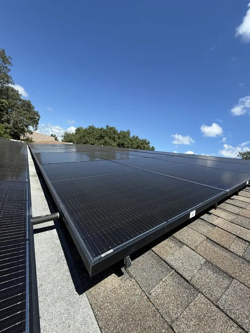 Clean solar panels on a shingle roof under blue sky