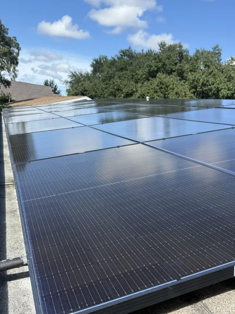 Glossy clean solar panels reflecting blue sky and clouds