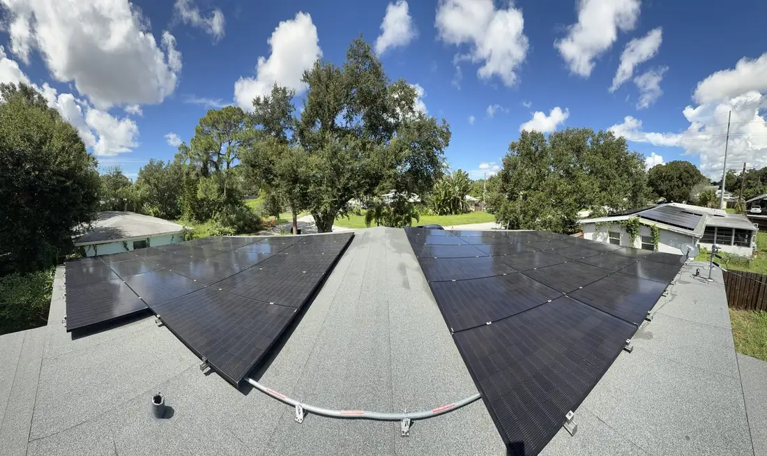 Wide-angle view of clean solar panels on both sides of a roof ridge